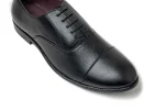 Close up of black leather oxford dress shoes with discreet brogue perforations