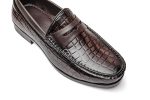 Brown leather loafers with a crocodile pores and skin texture and gold metallic gildings on the toes.