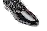The black leather-based slip-on footwear have white floral embroidery on the toes and heels.